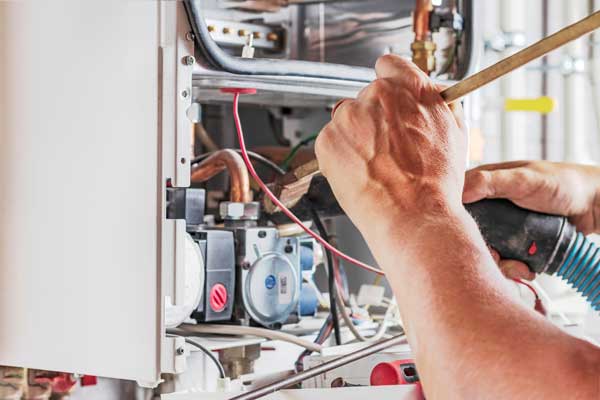 Image of a workman with the cover off a boiler, cleaning with a vacuum