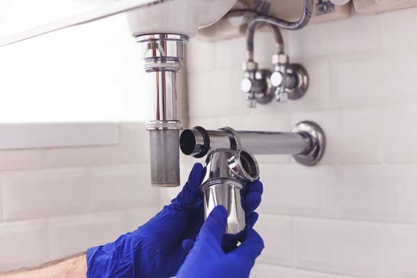 Image of a plumber fitting the pipework under a sink basin